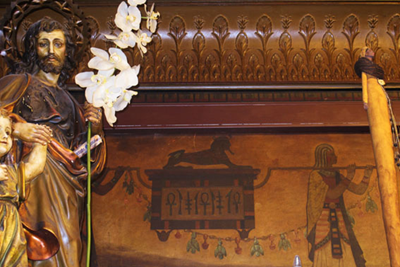 Motivos egipcios pintados en la pared de Fantoba. Un friso de madera con motivos nilóticos y una figura de un santo con unas flores. 